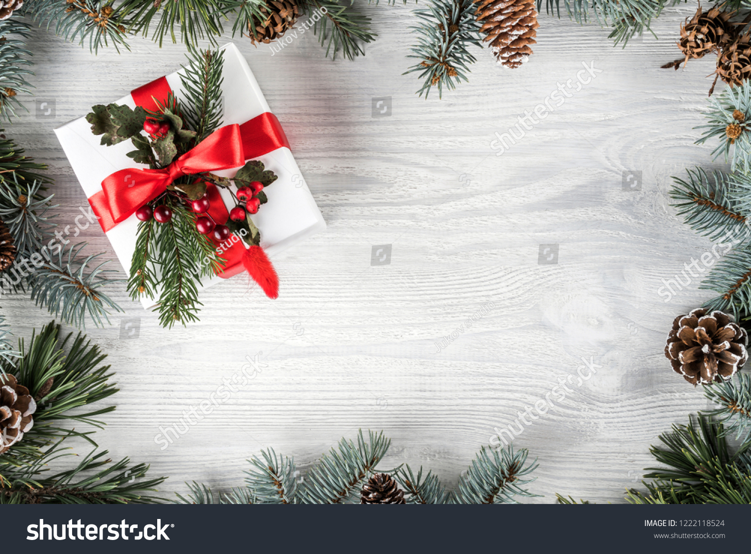 Creative frame made of Christmas fir branches on white wooden background with gift box, pine cones. Xmas and New Year theme. Flat lay, top view #1222118524