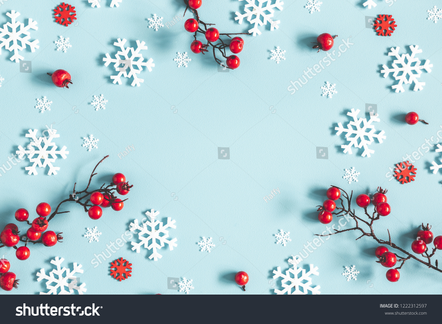 Christmas or winter composition. Frame made of snowflakes and red berries on pastel blue background. Christmas, winter, new year concept. Flat lay, top view, copy space #1222312597