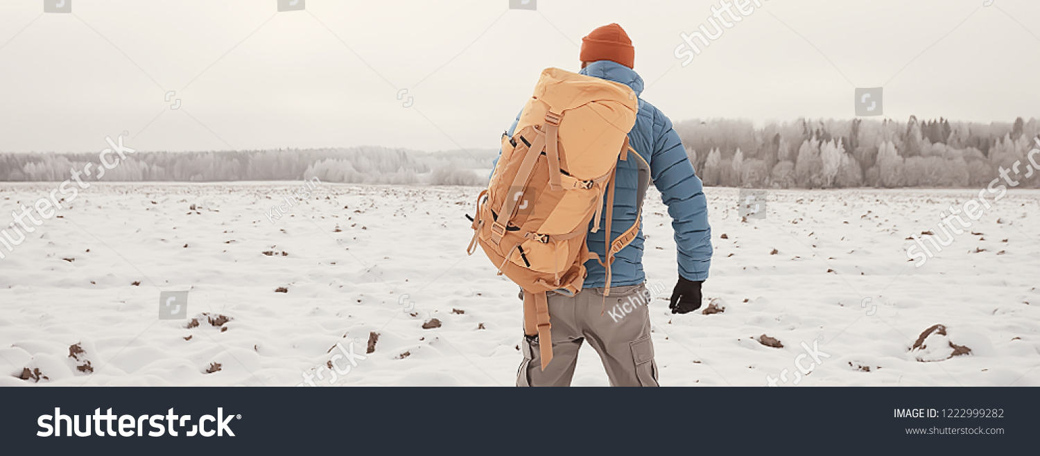 back view of  tourist with  backpack hiking in winter in Norway / one man carrying  backpack in a Norwegian winter landscape. #1222999282