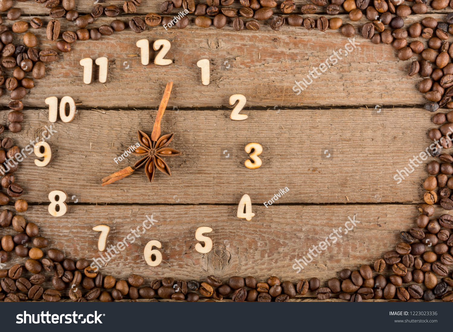 Decorative clock with wooden numerals and arrows made of cinnamon sticks, showing 8 o'clock, on a wooden background and a frame of coffee beans. Kitchen, advertising, banner, Copy space,  Flat Lay. #1223023336