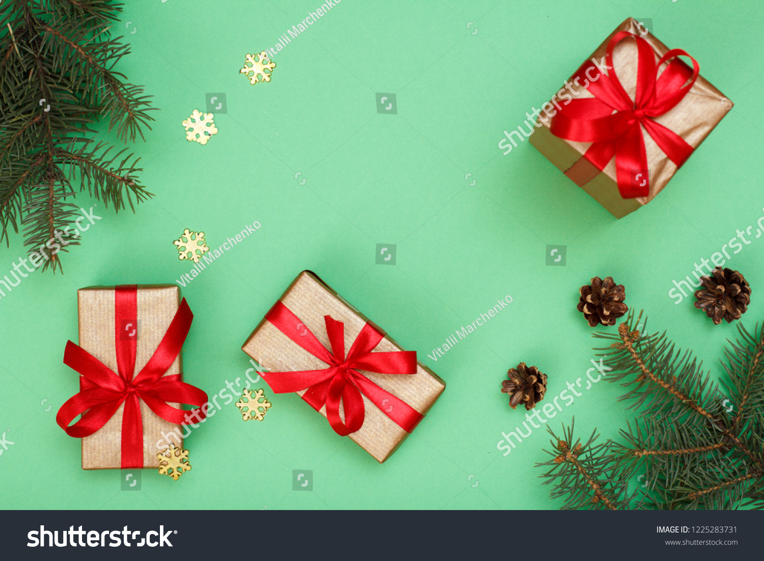 Christmas decoration. Gift boxes, fir tree branches with cones and decorative snowflakes on green background. Top view. Christmas greeting card concept. #1225283731