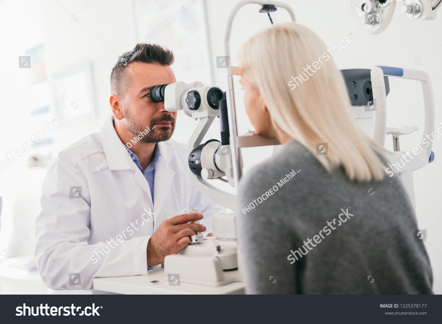 Optician checking his patient's eyes. Medical examination, proffesional optic machine. #1225378177
