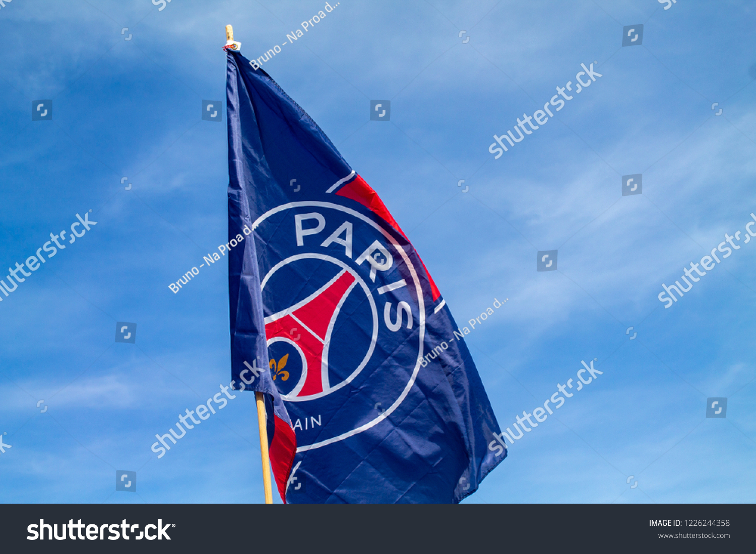 Paris Saint-Germain Football Club. The flag of PSG with a blue sky and clouds on the background in Paris, France. An UEFA Champions League team. #1226244358
