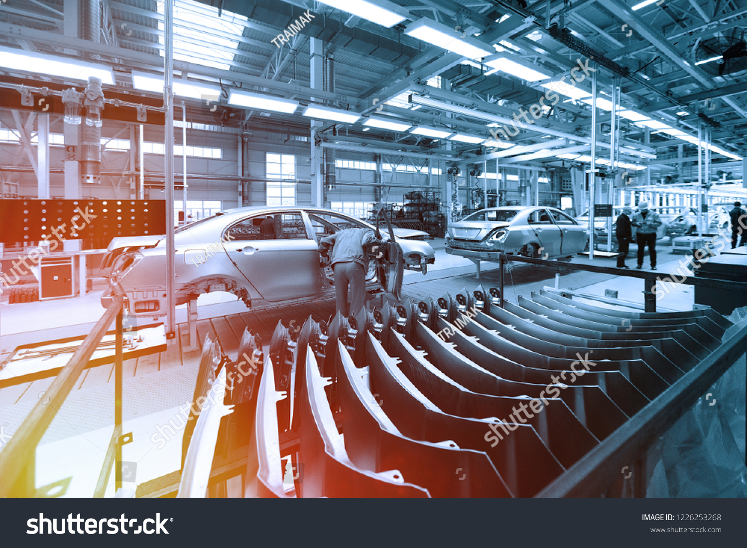 Worker looks into car body on production line. Factory for production of cars in blue. Modern automotive industry. Blue tone #1226253268