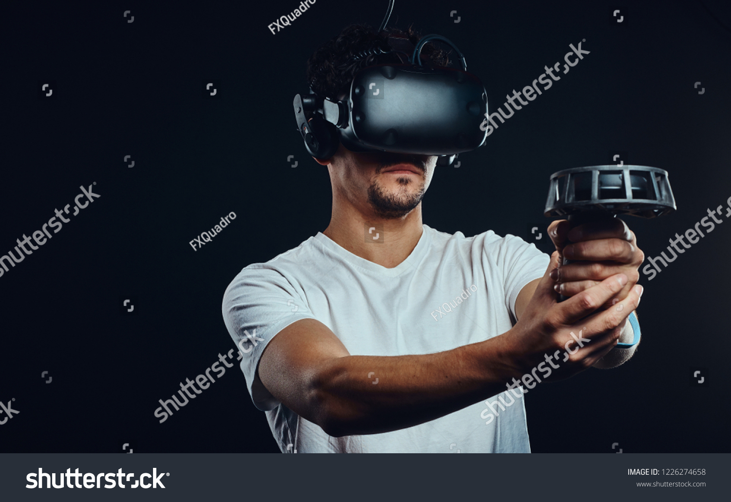 Man with bristle dressed in white shirt playing games with virtual reality goggles. #1226274658