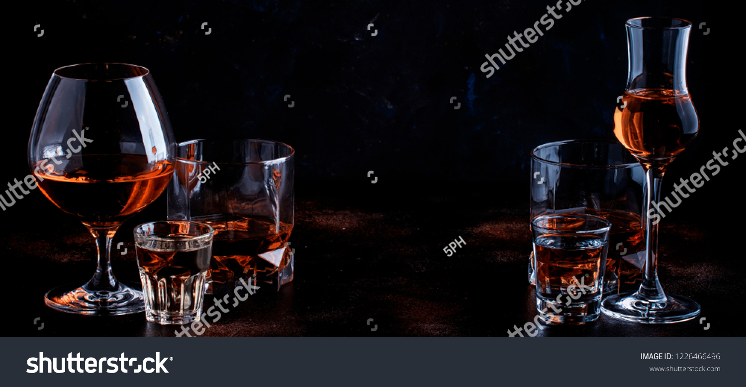 Selection of strong alcoholic drinks in glasses and shot glass in assortent: vodka, rum, cognac, tequila, brandy and whiskey. Dark vintage background, selective focus, copy space #1226466496