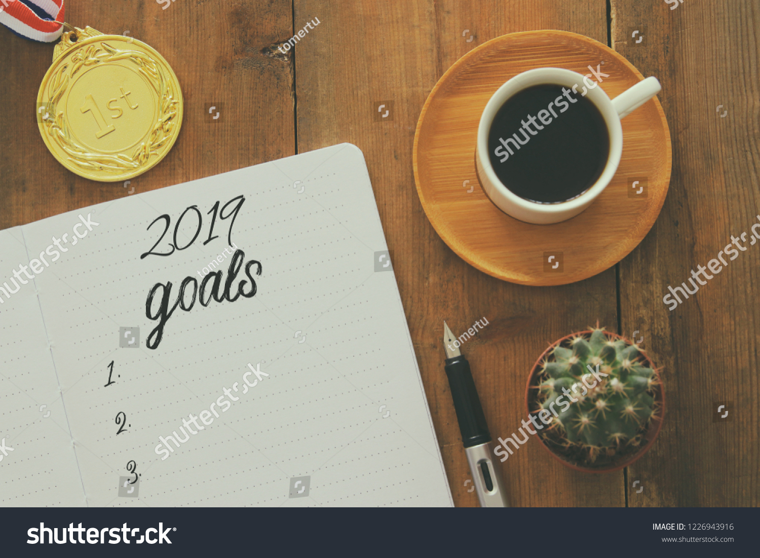 Top view 2019 goals list with notebook, cup of coffee over wooden desk #1226943916