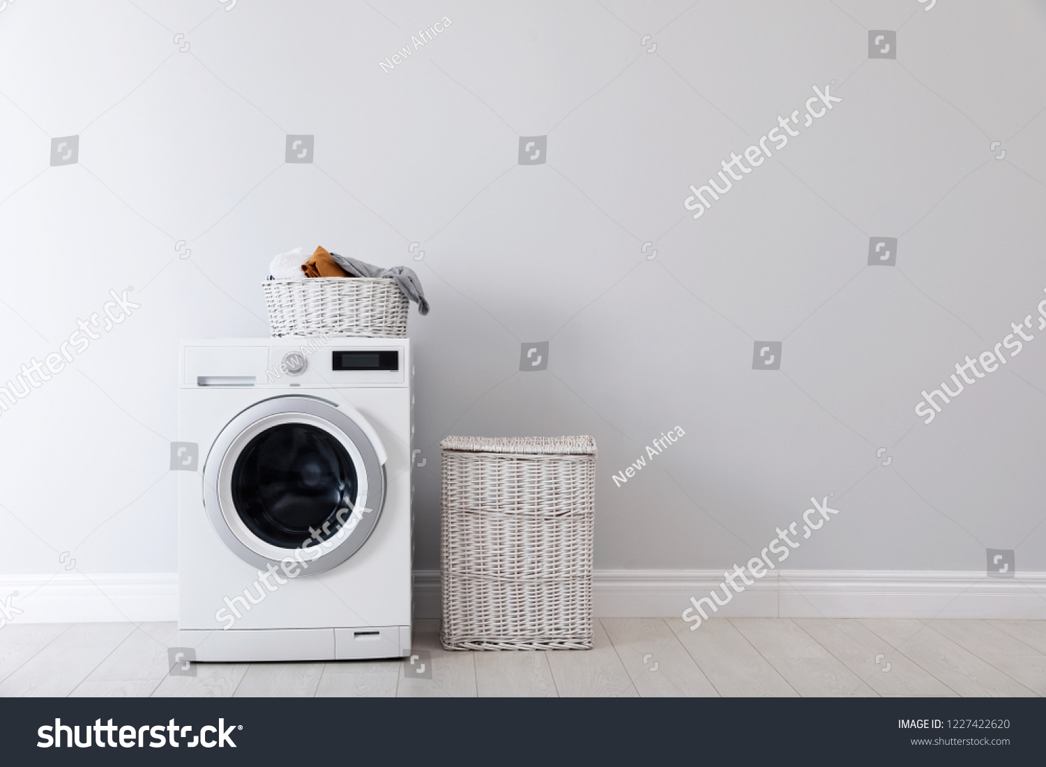 Washing machine with laundry and basket near wall. Space for text #1227422620