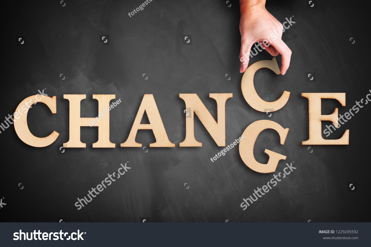 hand is moving a wooden letter, turning the word "change" to "chance" on a blackboard #1229205592