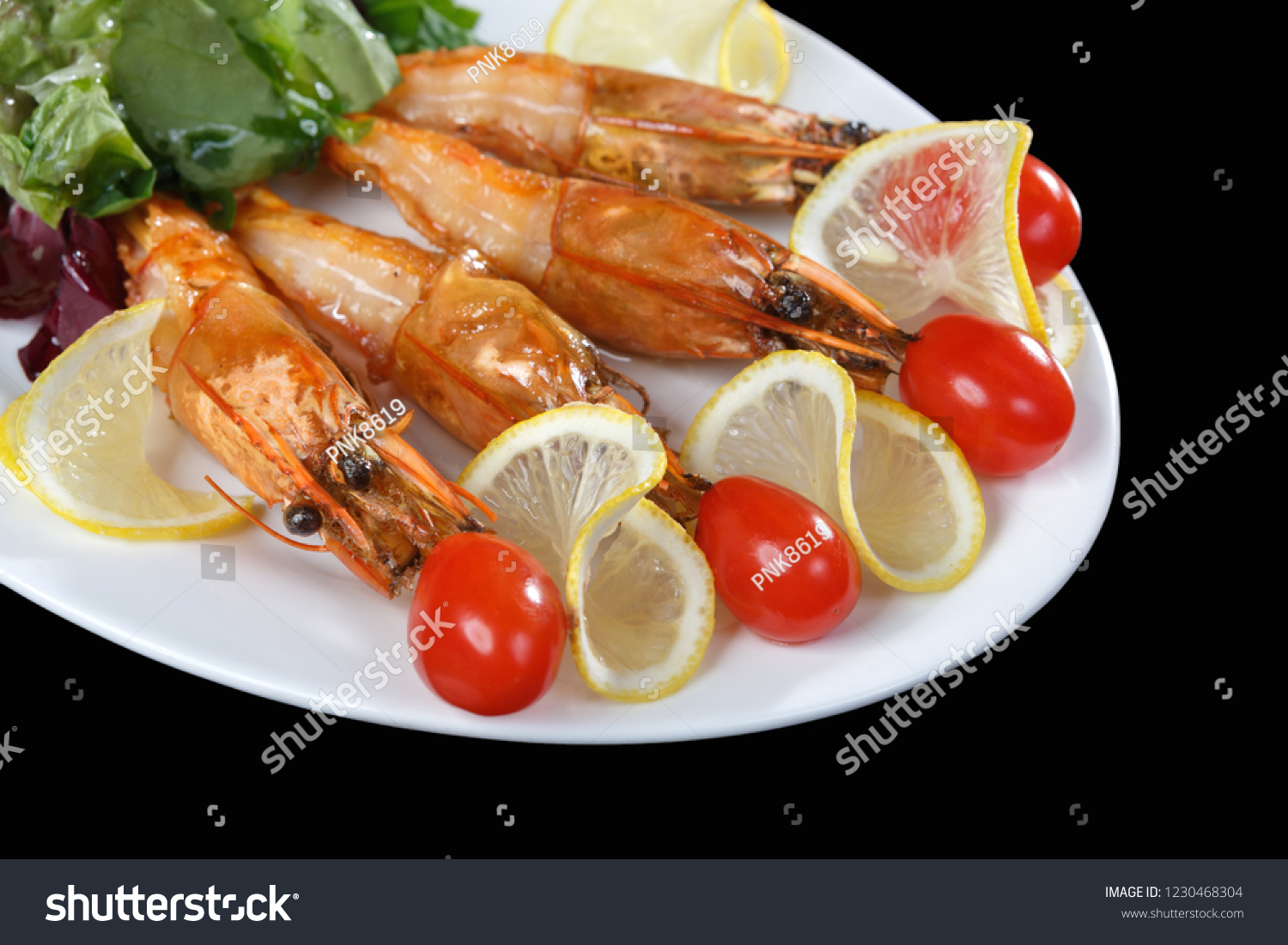 Shrimps, tomatoes and lemon are beautifully laid out on a dish on a black background. Freshly prepared shrimp #1230468304