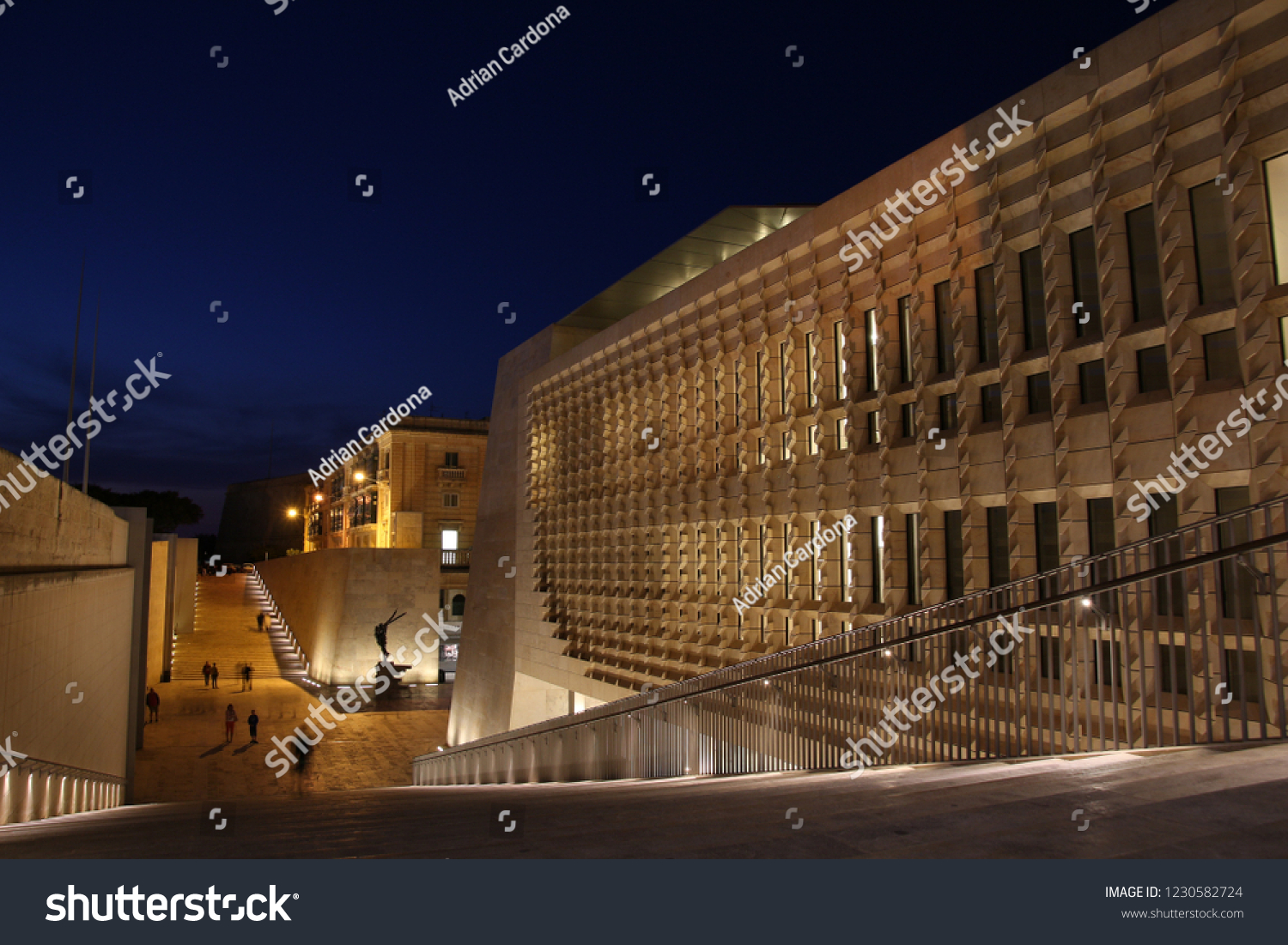 Evening strollers walk past the City Gate and Parliament buildings at the entrance to Valletta. Project was designed by architect Renzo Piano and built between 2011-2015 #1230582724