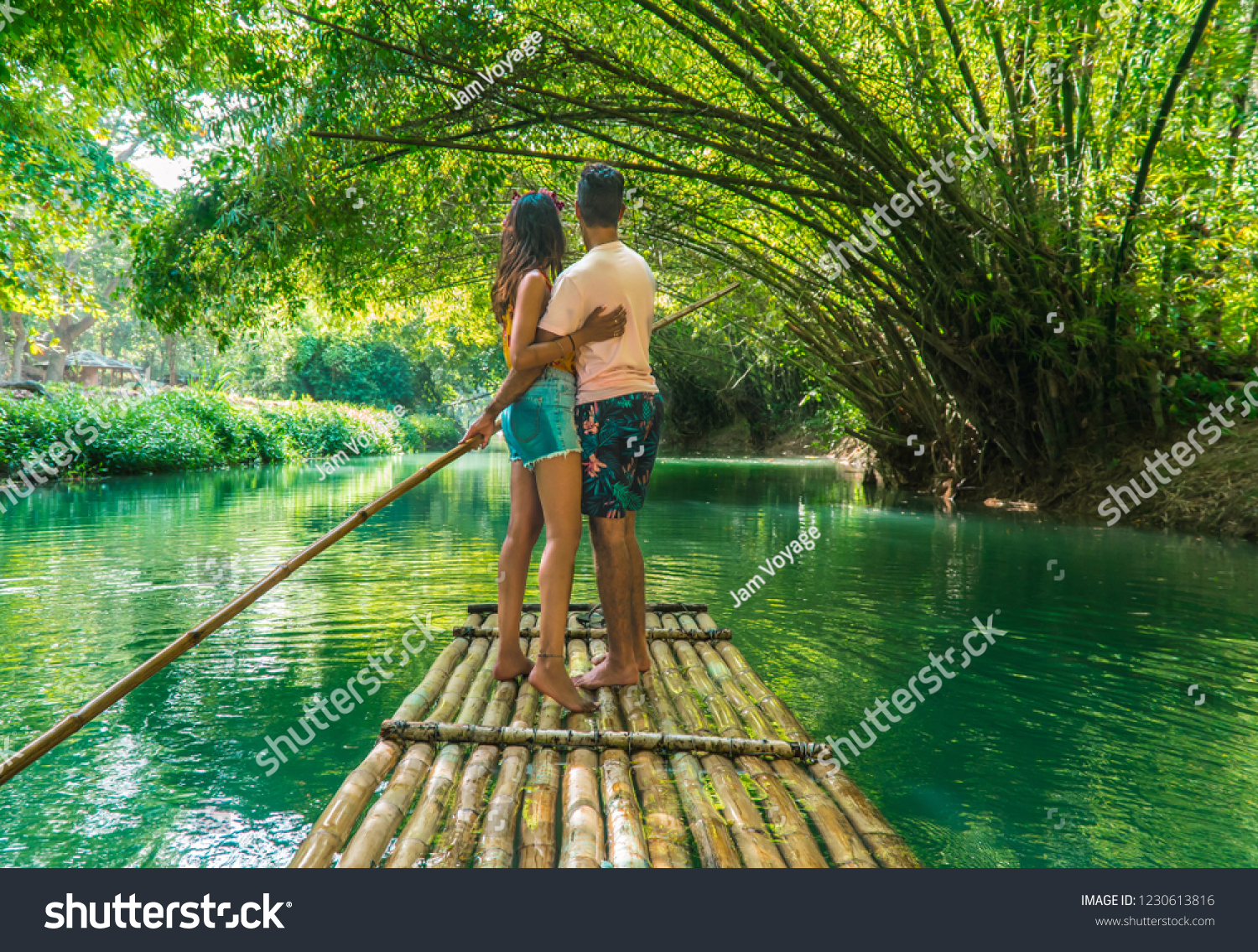Happy couple hugging and standing on bamboo raft, whilst on  cruise along Martha Brae river. Shot on romantic vacation in Montego Bay, Jamaica, Caribbean #1230613816