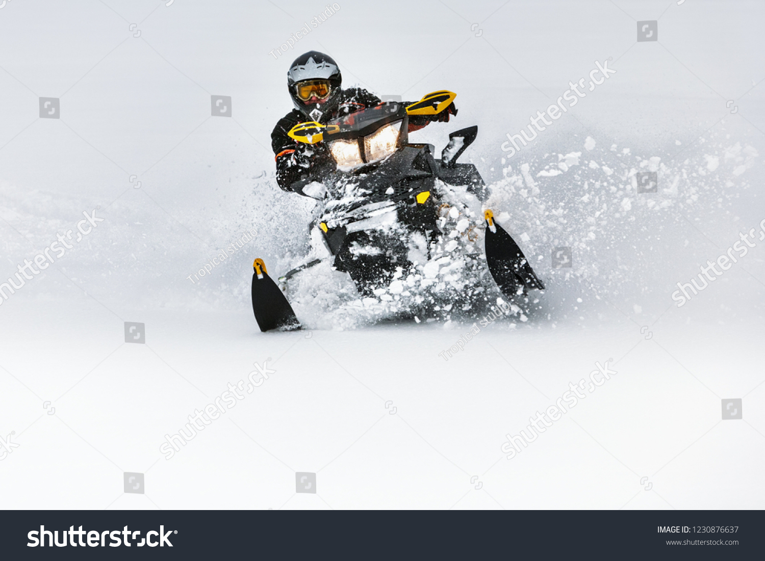 In deep snowdrift snowmobile rider make fast turn. Riding with fun in deep snow powder during backcountry tour. Extreme sport adventure, outdoor activity during winter holiday on ski mountain resort. #1230876637