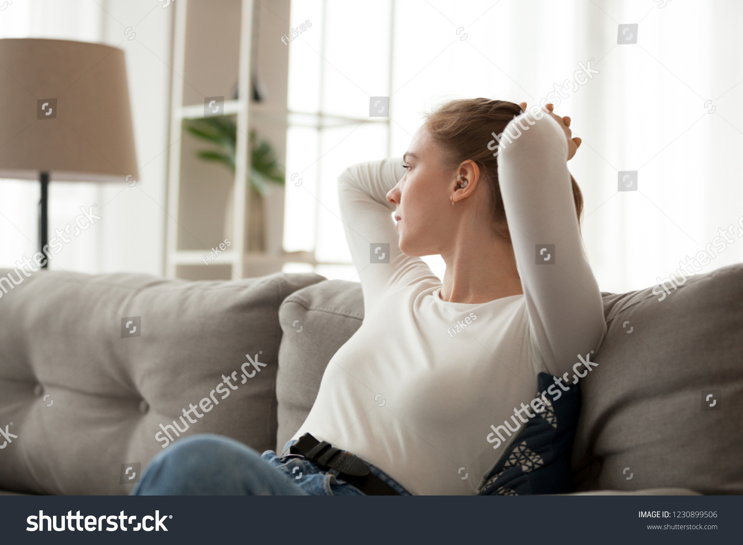 Thoughtful girl stretch sitting on cozy couch looking in distance considering, dreamy female relax at home thinking of future or making plans, distracted young woman rest on sofa lost in thoughts #1230899506