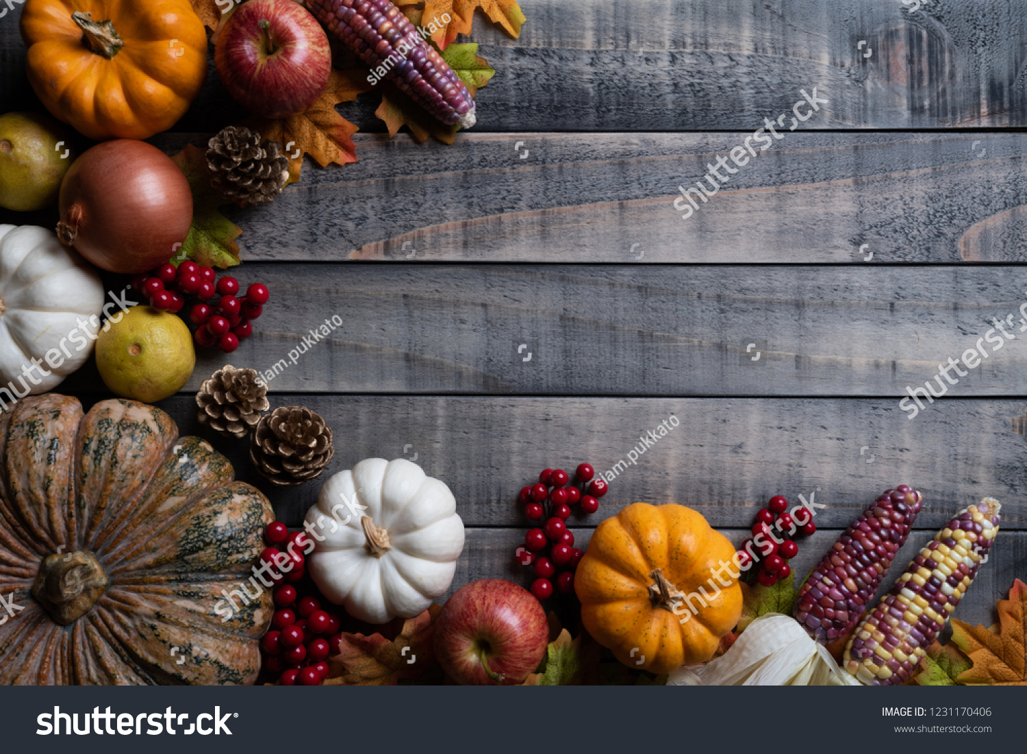 Top view of  Autumn maple leaves with Pumpkin, apple, corn and red berries on old wooden background. Thanksgiving day concept. #1231170406