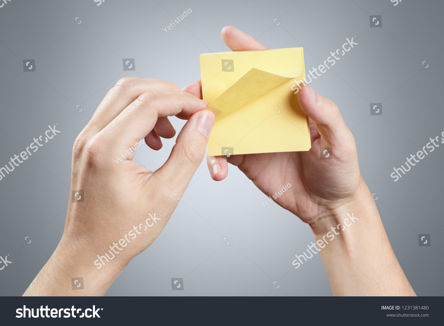 Hands holding a stack of yellow stickers on grey background #1231381480
