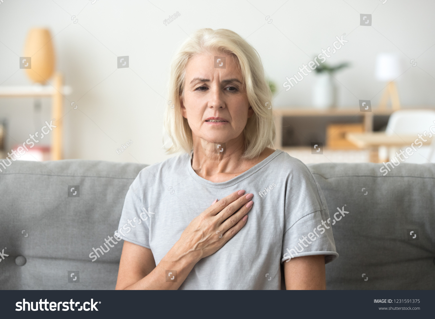 Upset stressed mature middle aged woman feeling pain ache touching chest having heart attack, sad worried senior older lady suffers from heartache at home, infarction or female heart disease concept #1231591375