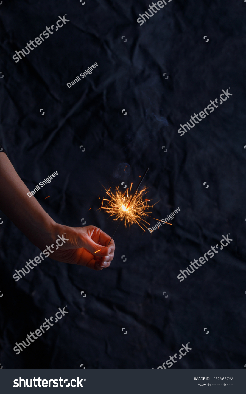 Female hand holding a burning sparkler. Christmas sparkler holiday background for xmas new year. Abstract Sparklers for celebration. #1232363788