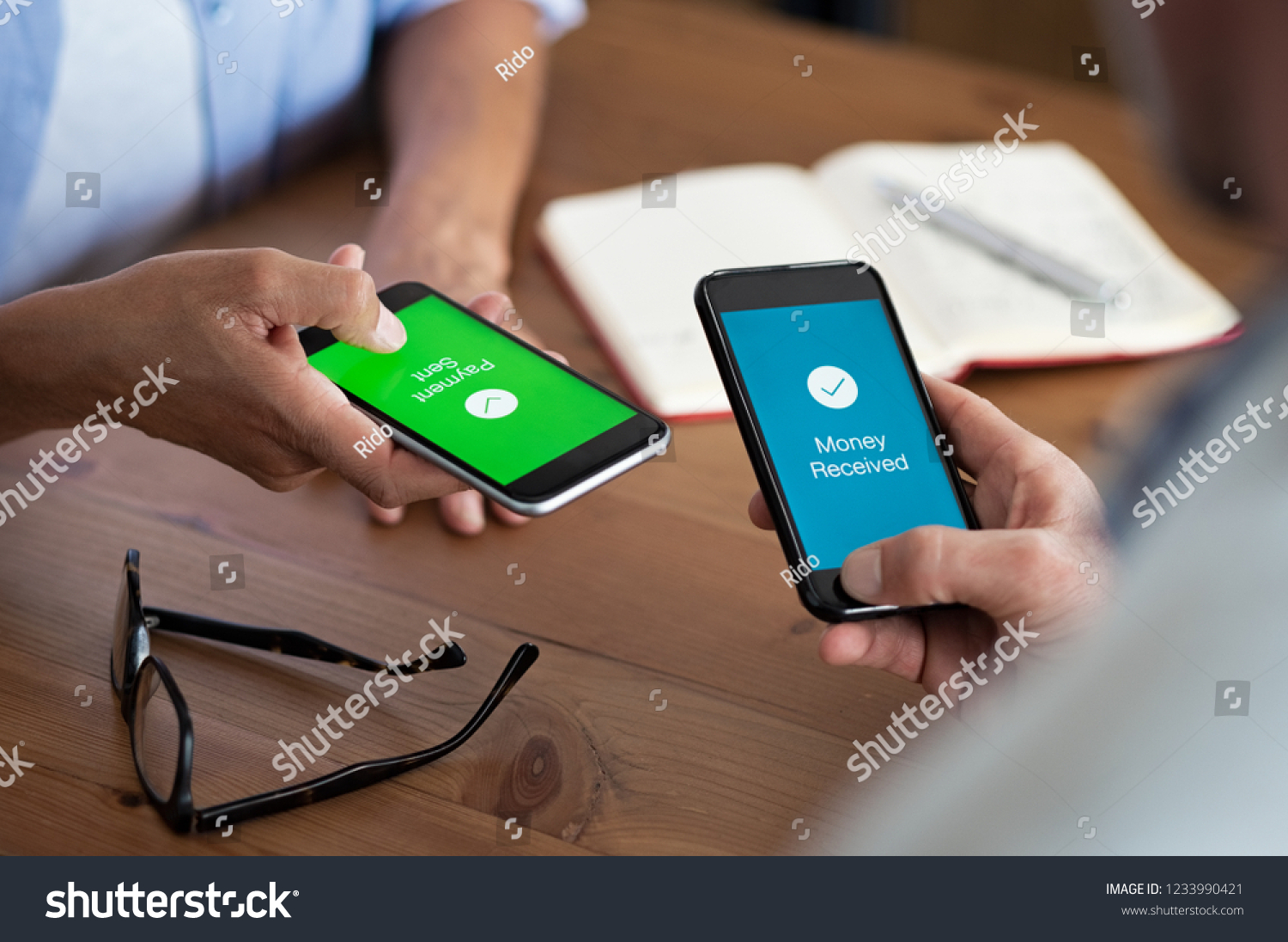 Closeup hands holding mobile phone with application for send and receive money. Man and woman holding smartphone and making payment transaction. Smart phone screen displaying payment sent. #1233990421