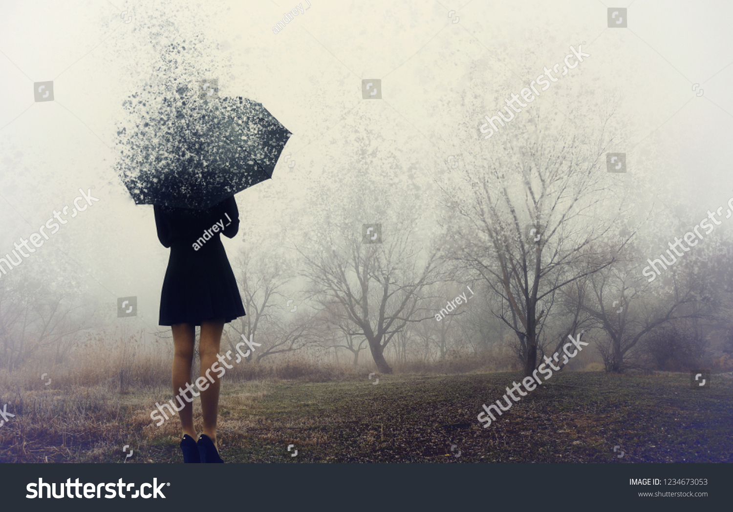 Girl with umbrella standing on the field with trees.