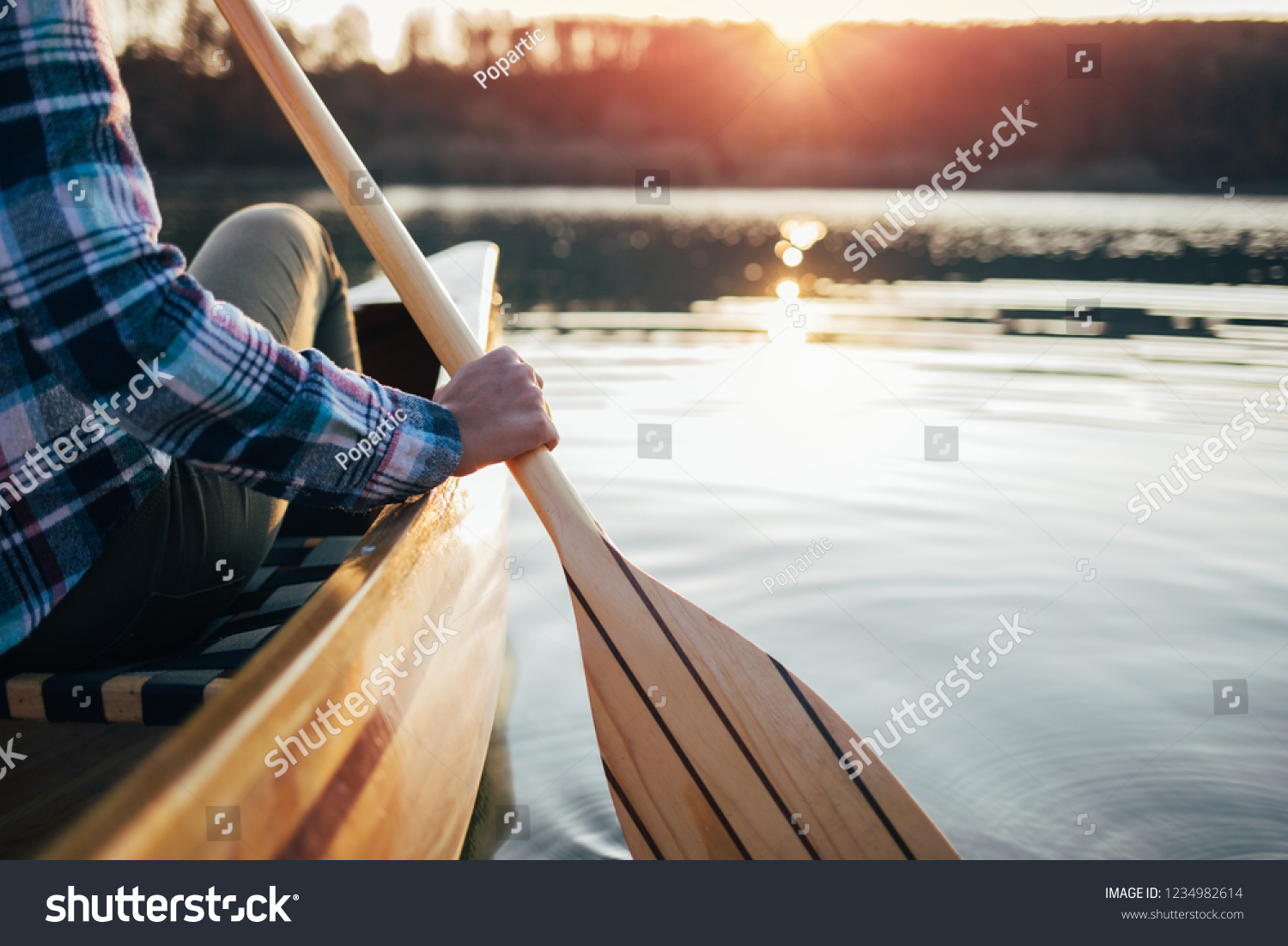 Close up of hipster girl holding canoe paddle. Canoeing on the sunset lake #1234982614