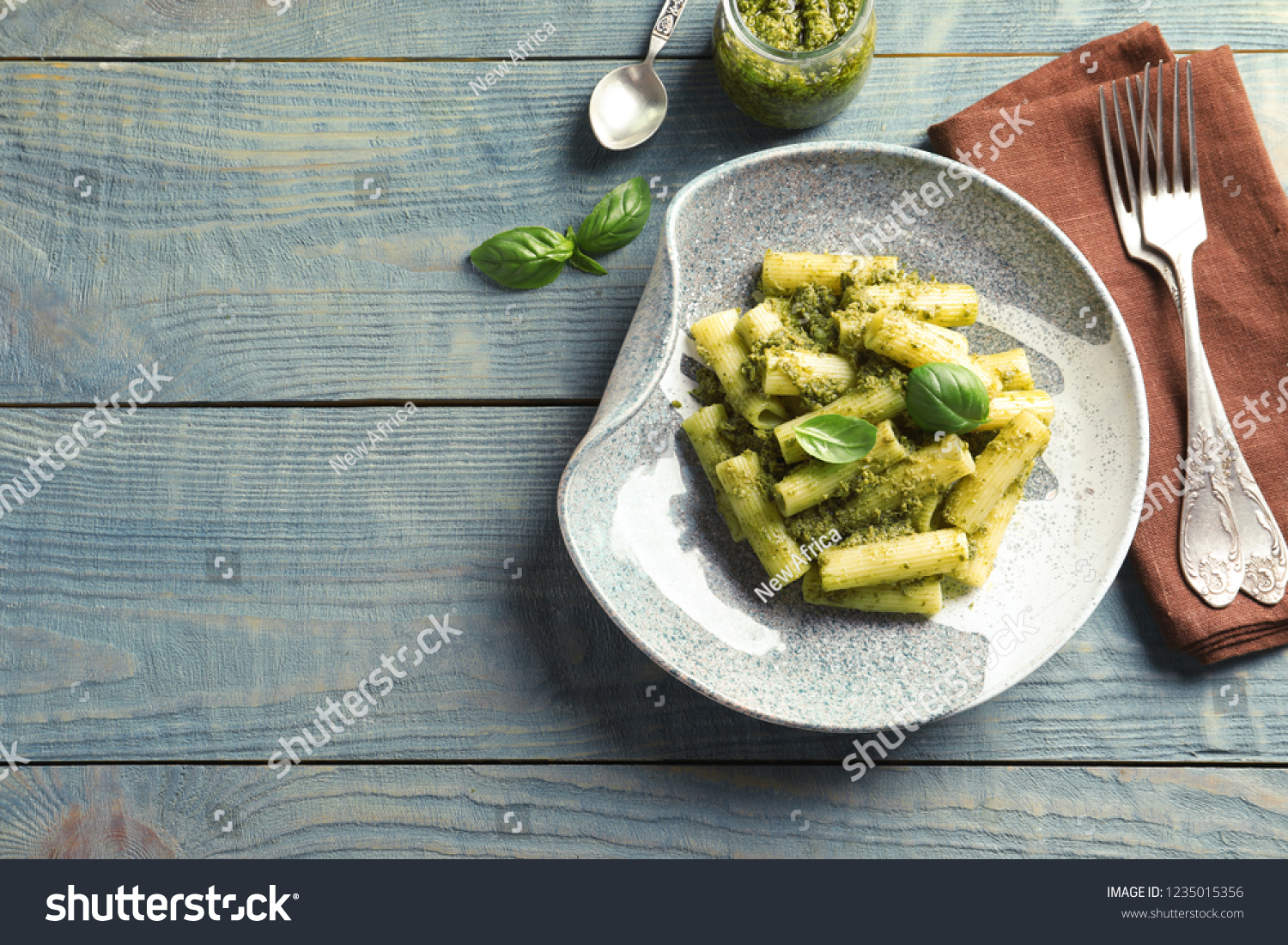 Flat lay composition with plate of delicious basil pesto pasta and space for text on wooden table #1235015356
