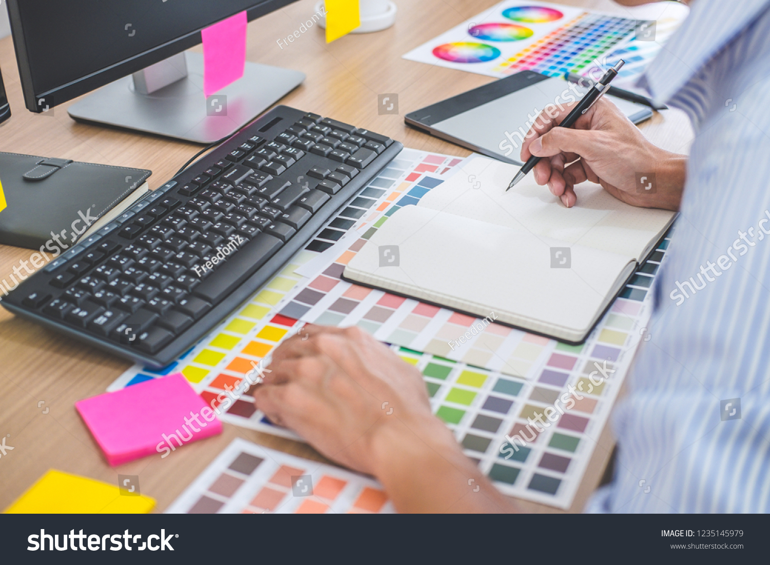 Image of male creative graphic designer working on color selection and drawing on graphics tablet at workplace with work tools and accessories in workspace. #1235145979