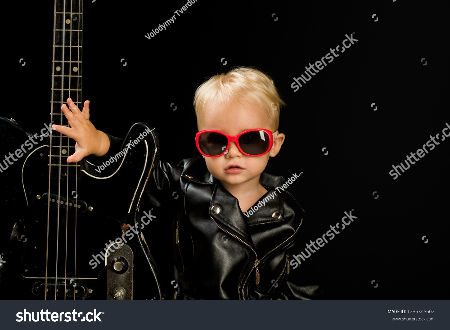 Music for everyone. Adorable small music fan. Small musician. Little rock star. Child boy with guitar. Little guitarist in rocker jacket. Rock style child. Rock and roll music performer. #1235345602
