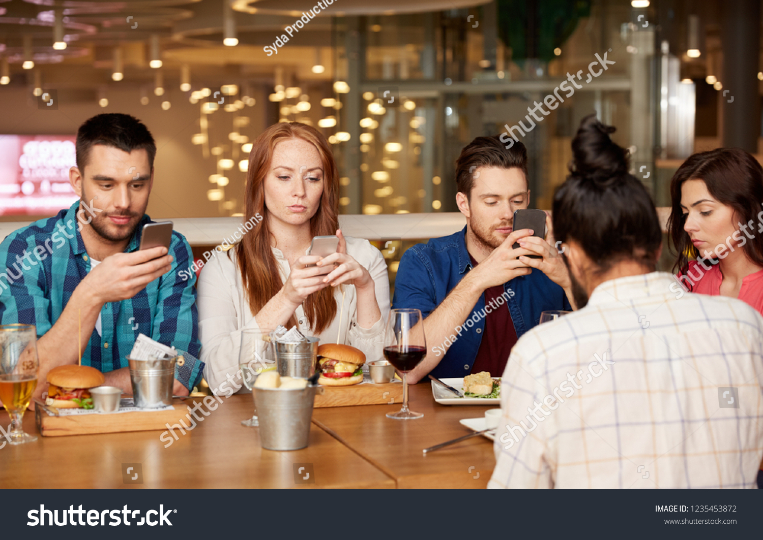 leisure, technology, lifestyle and people concept - friends with smartphones dining at restaurant #1235453872