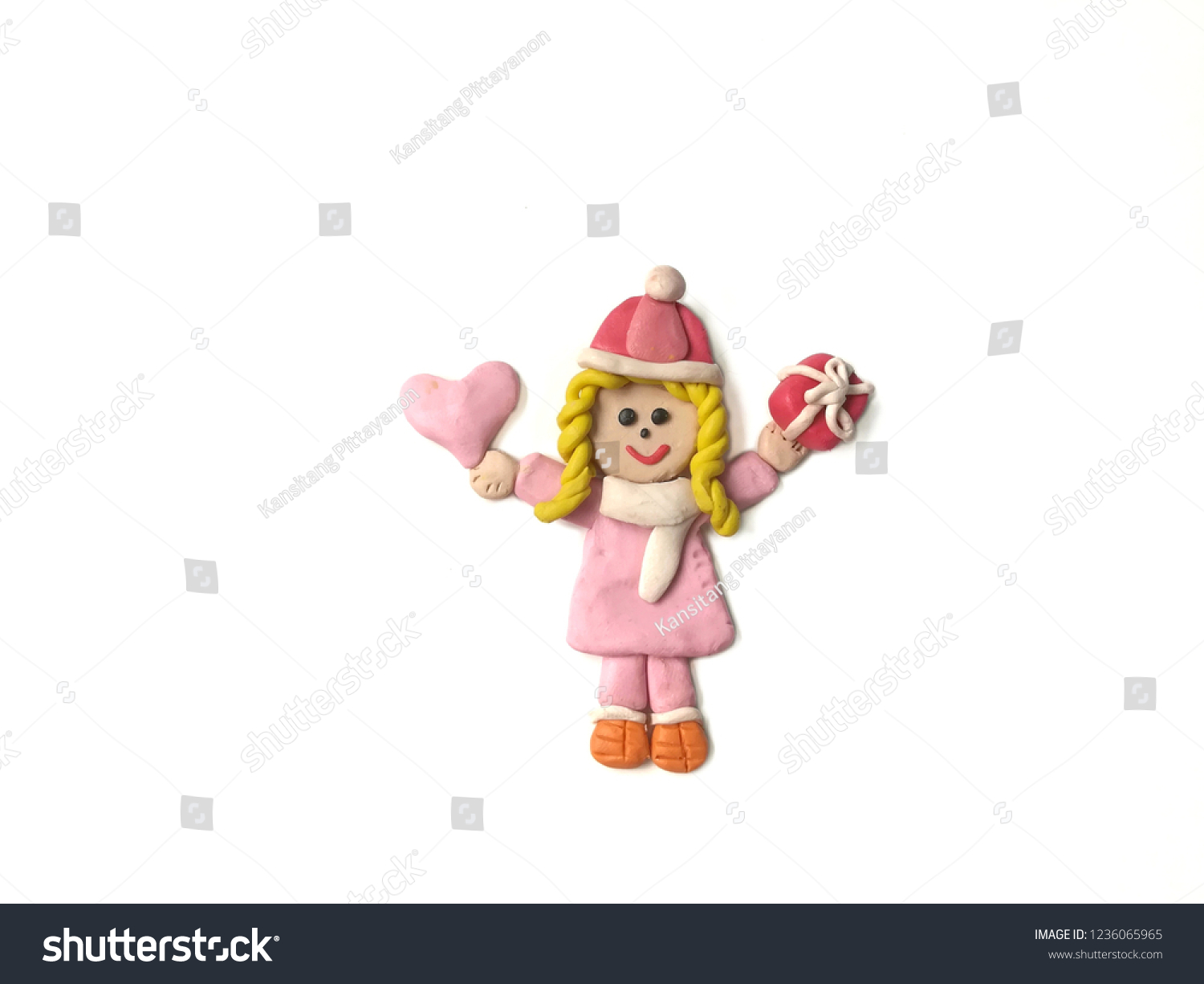Pretty girl holding the pink heart and red gift box made from plasticine clay placed on white background, cute child dough wearing a coat in winter festival #1236065965