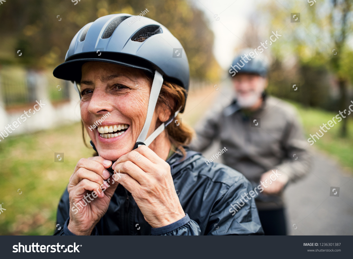 Active senior couple with electrobikes standing outdoors on a road in nature. #1236301387