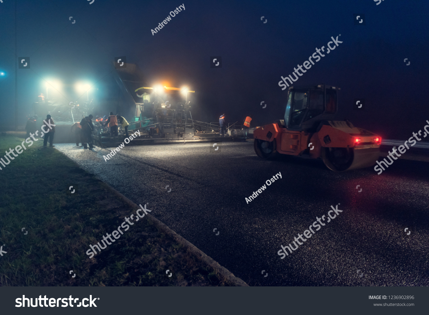 Laying asphalt paver at night with headlights. Road construction. #1236902896