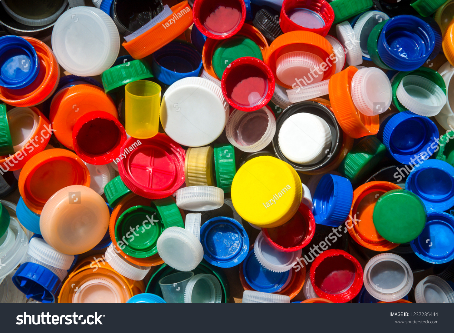 Pile of brightly colored plastic bottle tops gathered on the beach to highlight the crisis of worldwide ocean pollution #1237285444