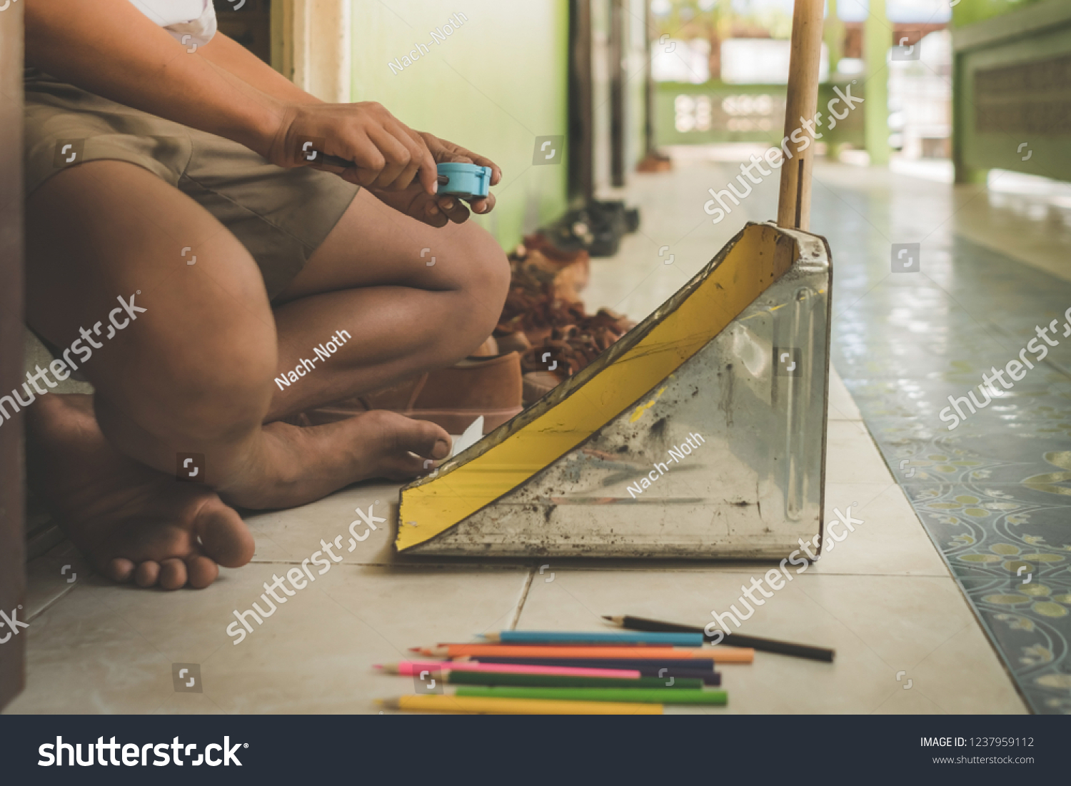 Elementary student sharpen the color pencil into the dustpan in front of classroom #1237959112