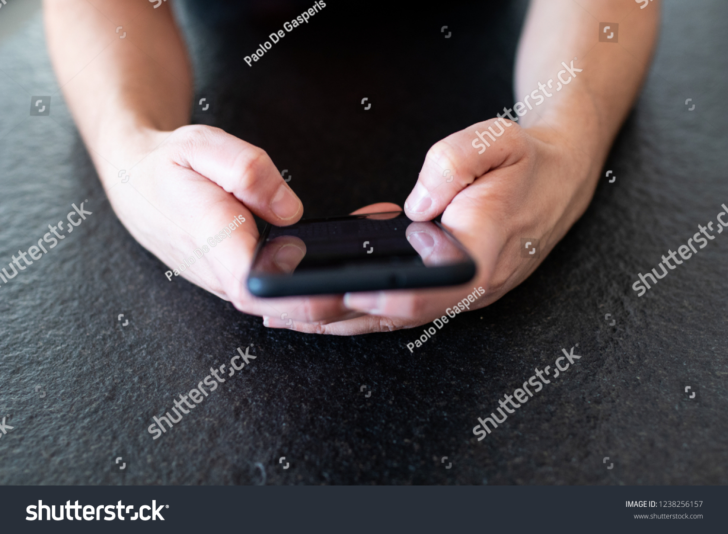woman's hand using a smartphone to chat on social network with friends. Finger tapping on touch screen, using smartphone on a black granite table at the coffee desk #1238256157