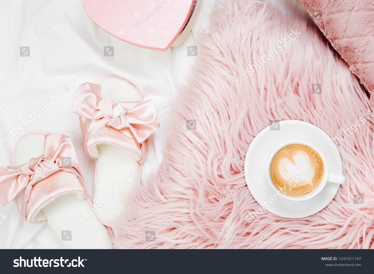 Morning concept. A cup of coffee on a pink pillow, slippers on the bed. Flat lay, top view #1241011147
