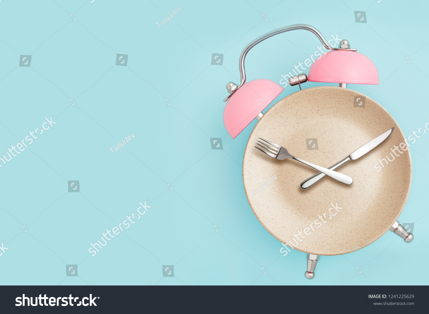 Alarm clock and plate with cutlery . Concept of intermittent fasting, lunchtime, diet and weight loss #1241225629