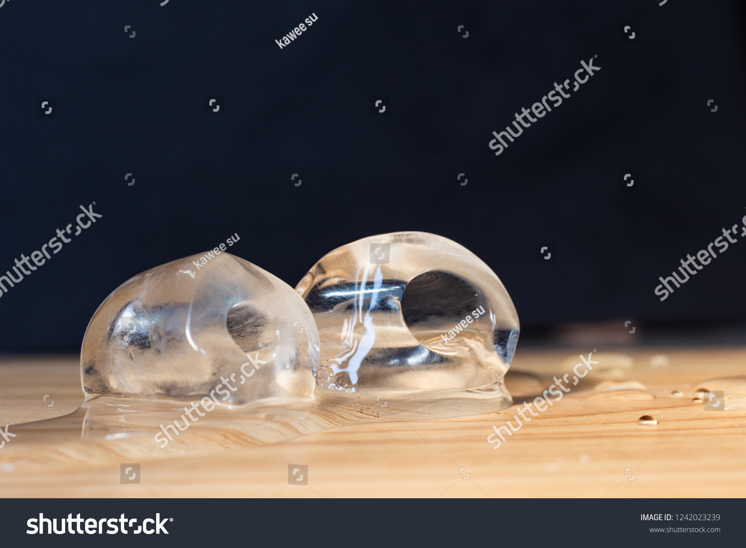 ice cubes-Ice cubes are melting;Ice cubes on wooden floor;Black background. #1242023239