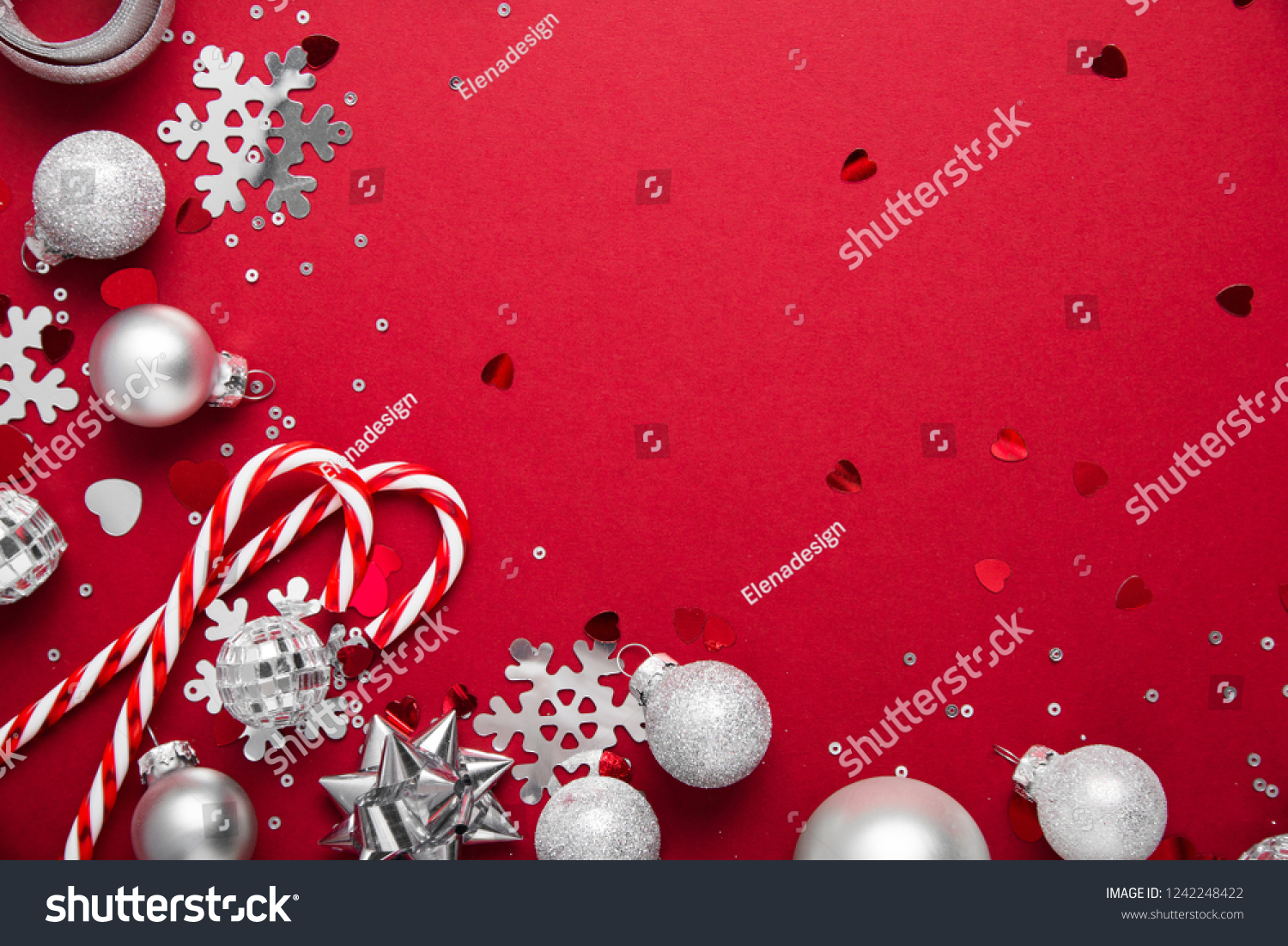 Merry Christmas and Happy Holidays greeting card, frame, banner. New Year. Noel. Christmas white and silver ornaments on red background top view. Winter holiday xmas theme. Flat lay. #1242248422