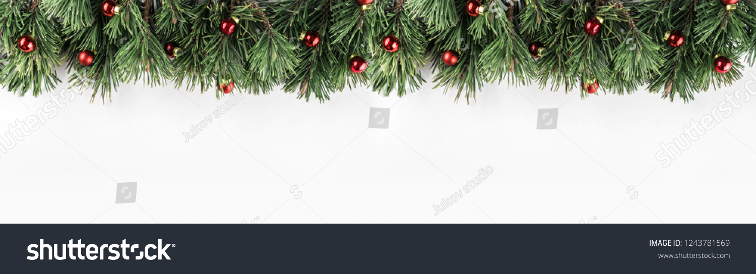 Christmas garland of Fir branches with red decoration on white background. Xmas and Happy New Year theme. Flat lay, top view, wide composition #1243781569
