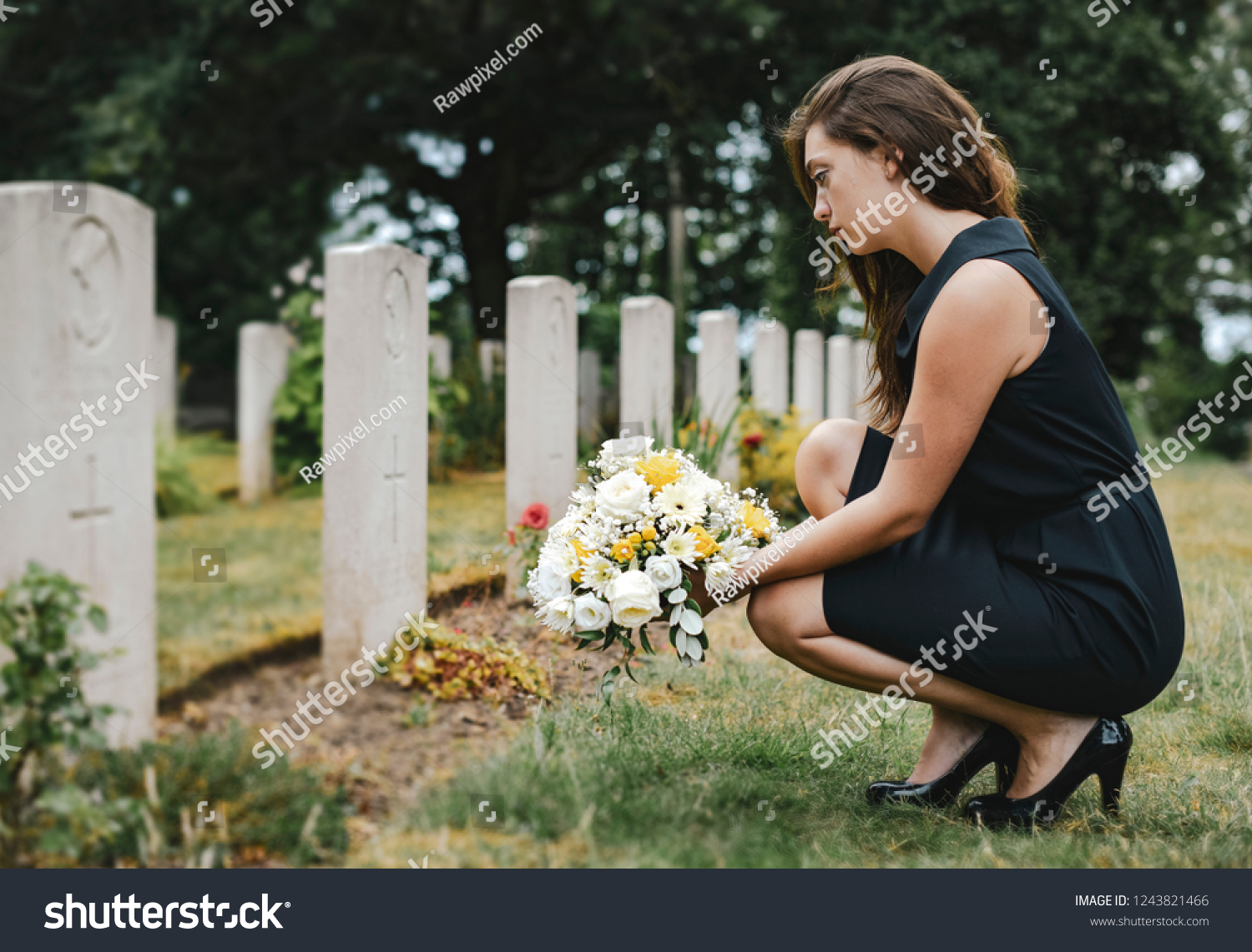 Young widow laying flowers at the grave #1243821466