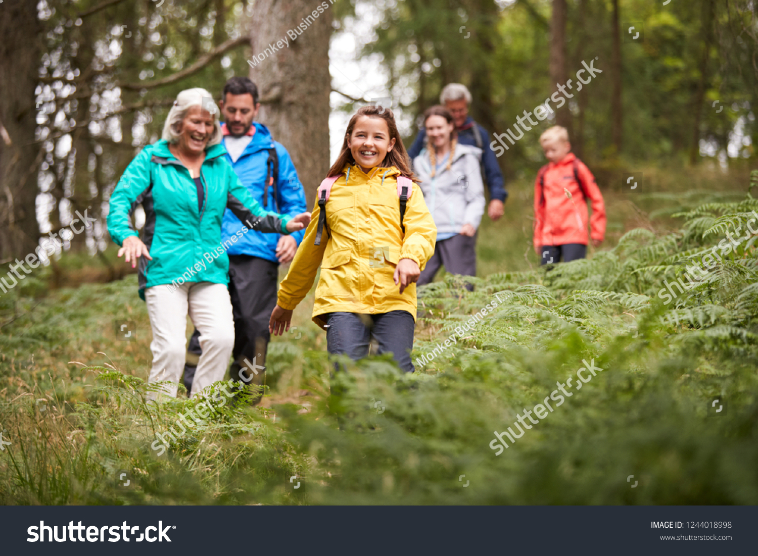 Multi generation family walking downhill on a trail in a forest during a camping holiday, Lake District, UK #1244018998
