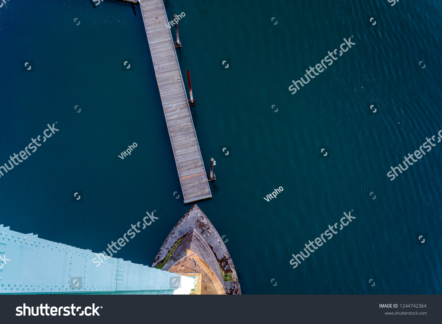 Top view of the support of the gothic St Johns bridge over the Willamette River in Portland with a small floating pier with pillars for mooring boats and yachts and dark water surface #1244742364