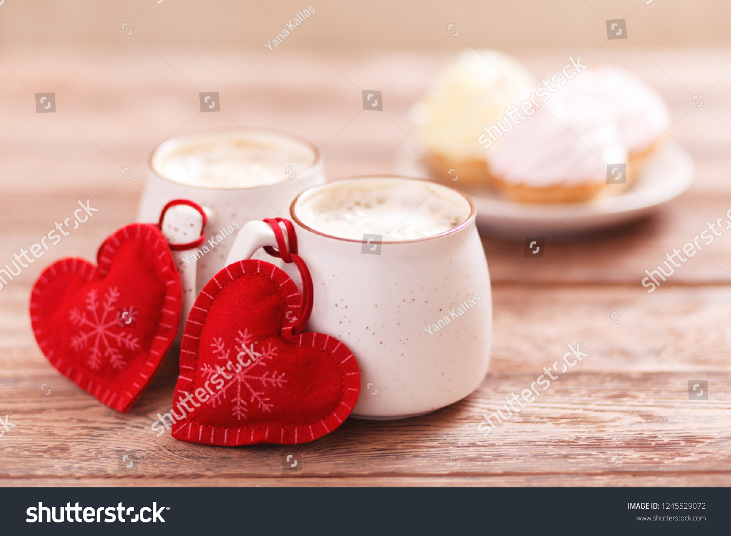 Background romantic mood. Two cups of coffee with decorative felt hearts for Valentine's Day or Birthday, Christmas. Wooden background. Cakes on blurred background. Selective focus, close-up #1245529072