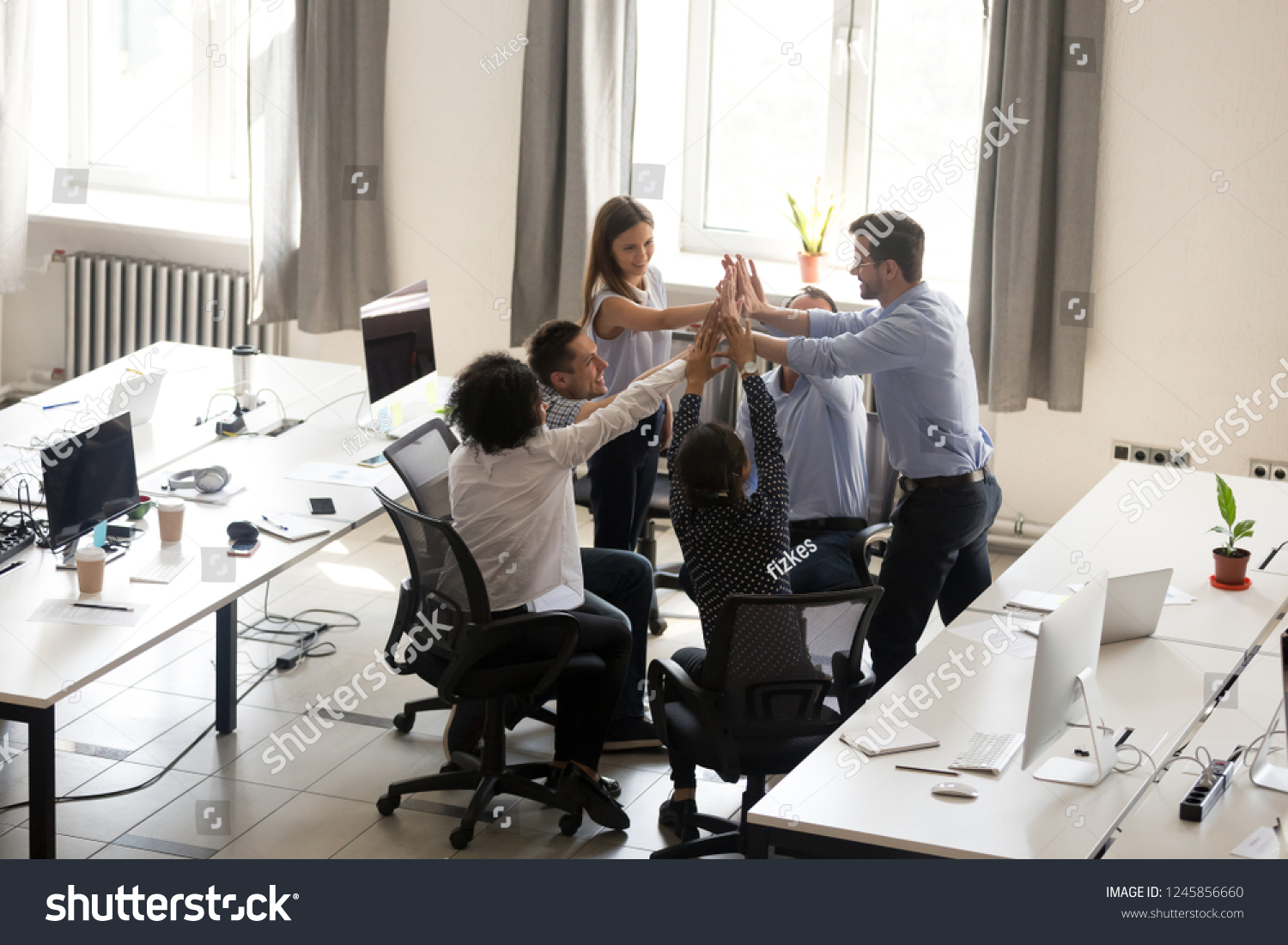 Excited multiracial office workers team giving high five together, celebrating successful teamwork results, involved in team building activity, good corporate relations, motivated by success #1245856660