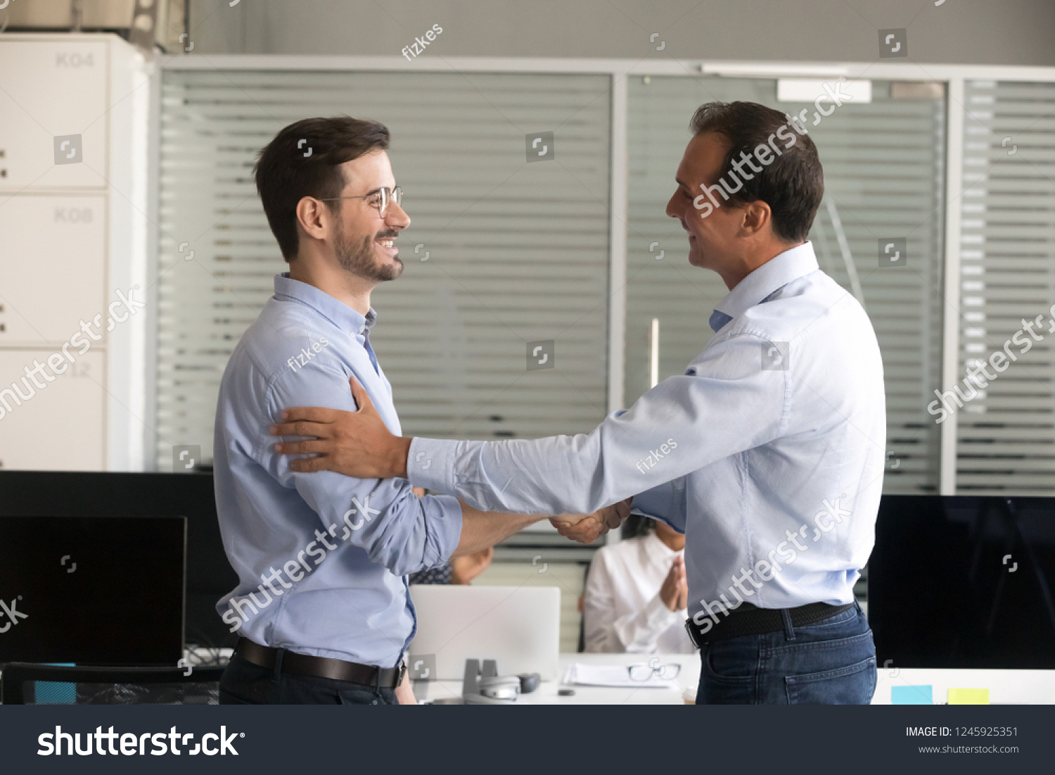 Friendly middle aged boss handshaking male successful employee, congratulate confident worker with promotion, business achievement, thank for good work results, expressing respect, rewarding #1245925351