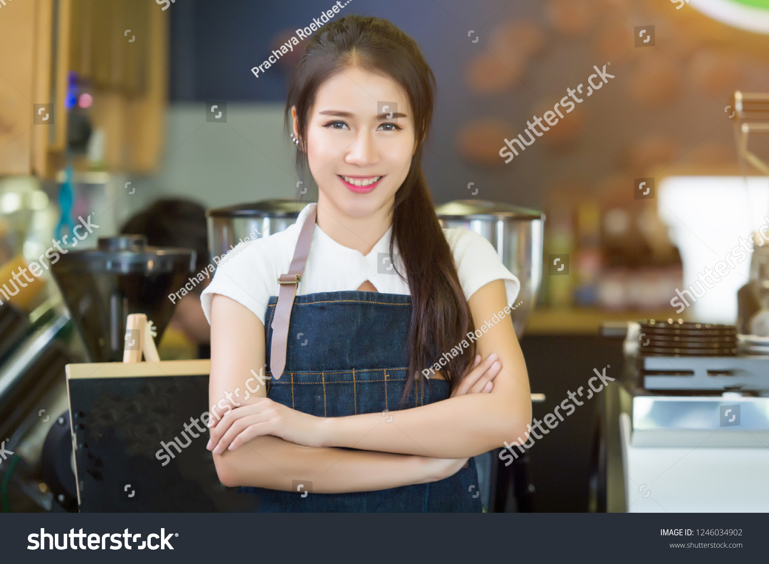 Young beautiful barista female in an apron preparing cup of coffee for customer in coffee shop. on demand #1246034902