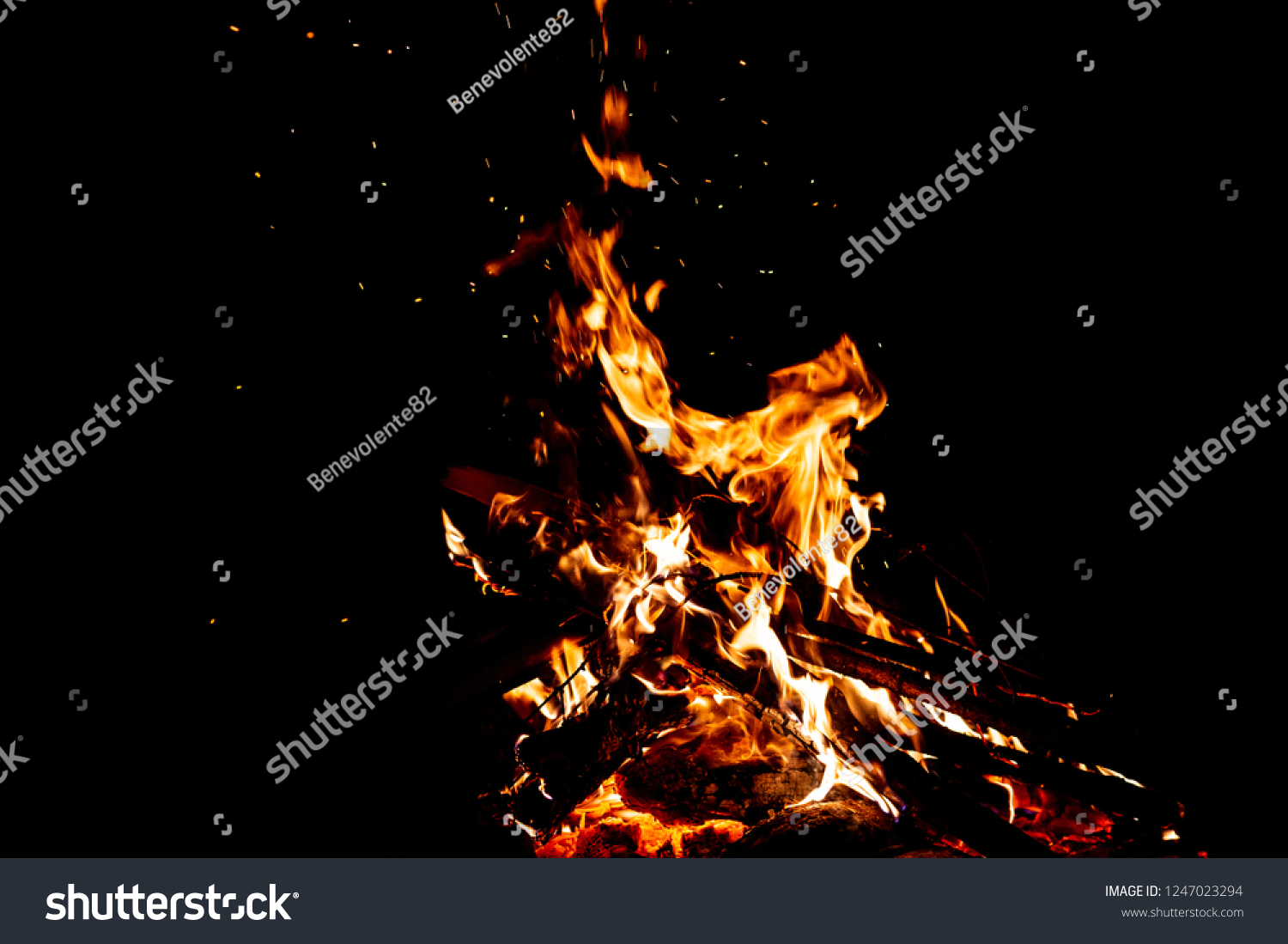 Burning woods with firesparks, flame and smoke. Strange weird odd elemental fiery figures on black background. Coal and ash. Abstract shapes at night. Bonfire outdoor on nature. Strenght of element #1247023294