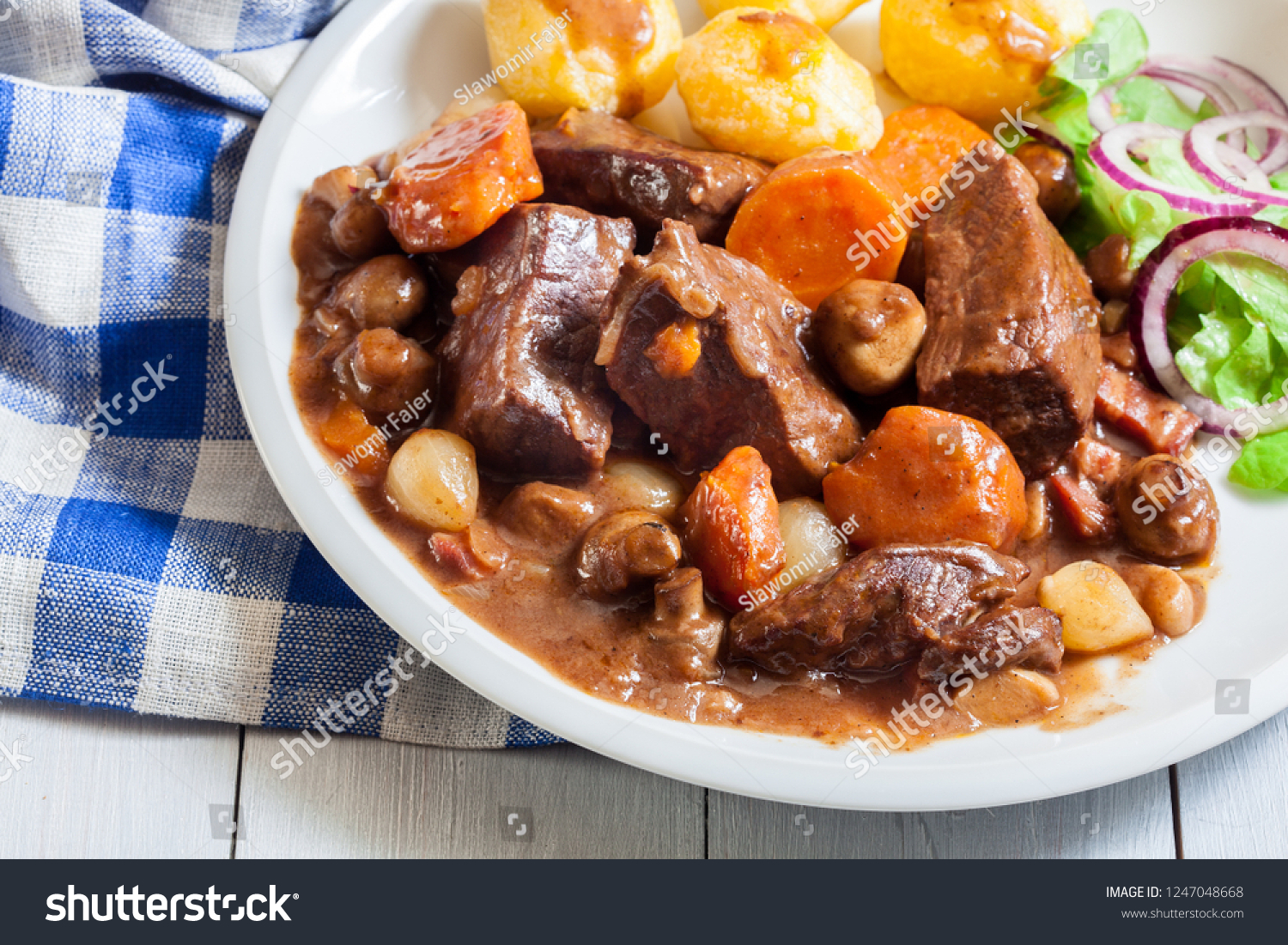 Beef Bourguignon stew served with baked potatoes on a plate. French cuisine #1247048668