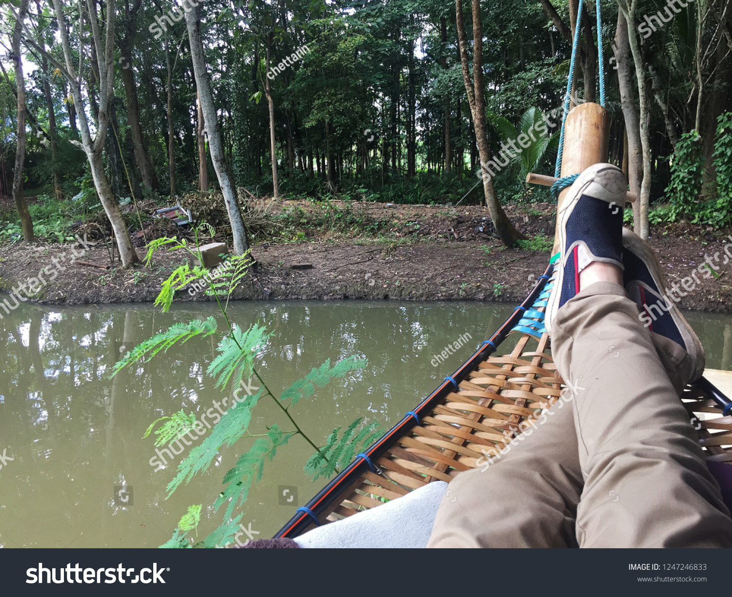 Lying on wooden cradle upon natural pond among green forest park #1247246833
